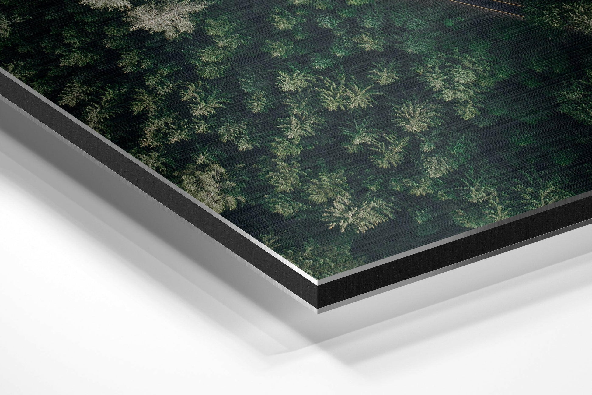 Angled view of brushed aluminum Dibond panel featuring fifty shades of green fern patterns on dark wood texture background.