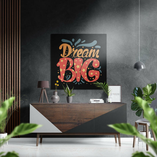 Coral and gold "Dream Big" typography with star pattern displayed on black canvas above wooden mid-century modern dresser in styled interior.