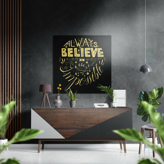 Modern living room interior with black and gold "Always Believe in the Impossible" wall art displayed above wooden dresser.