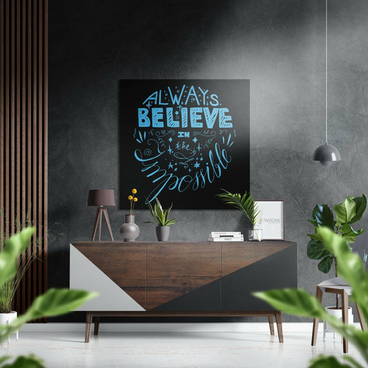 Modern living room with sky blue "Always Believe in the Impossible" quote on black wall art above wooden dresser with plants.