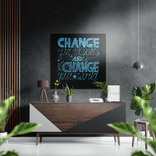Blue hand-lettered motivational quote on black aluminum wall art displayed above wooden mid-century dresser in modern living room setting.