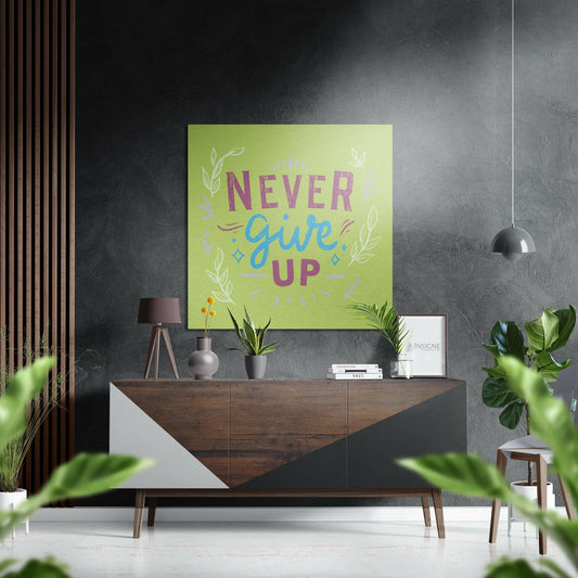 Lime green aluminum wall art with "Never Give Up" text in purple and blue letters, displayed above a wooden dresser in a modern interior setting.