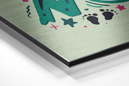 Close-up angled view of brushed aluminum composite panel with teal, pink, and black underwater-themed illustrations on light background.
