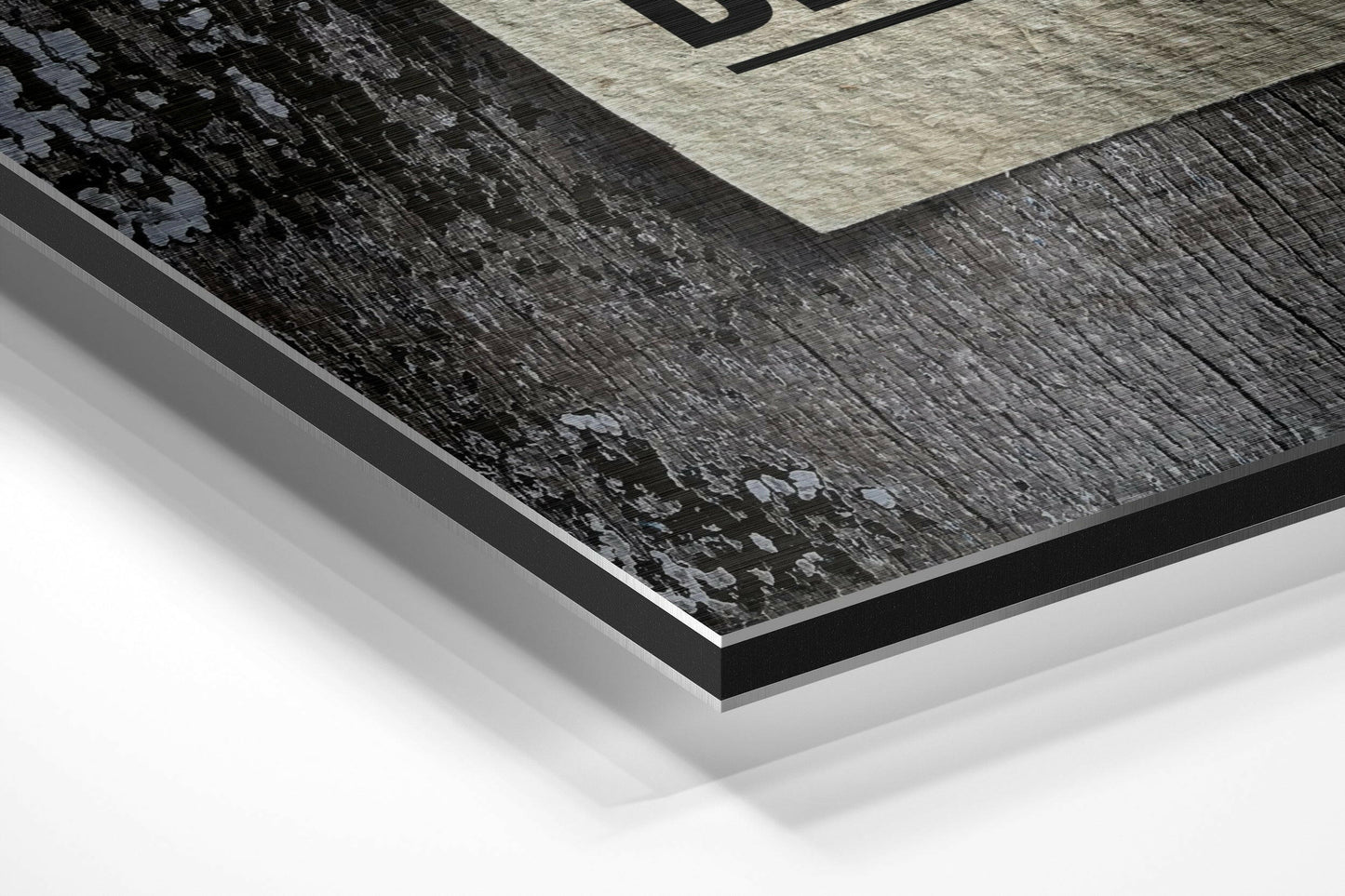 Close-up angled view of layered Dibond wall art showing black brushed aluminum surface with light gray and cream-colored geometric sections above.