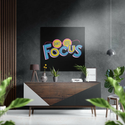 Colorful neon-style "Don't Lose Focus" artwork displayed on black wall above wooden dresser in modern grey interior.
