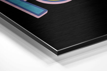 Close-up angled view of layered black brushed aluminium and white surface with colorful geometric design visible at top edge.