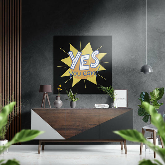 Motivational wall art with yellow starburst and "YES you can" text displayed above wooden console table in modern interior setting.