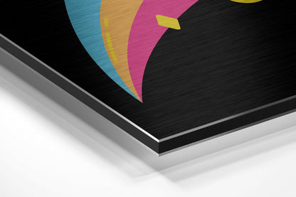 Angled perspective view of brushed aluminum dibond wall art featuring colorful geometric shapes in blue, gold, magenta, and yellow on black background.