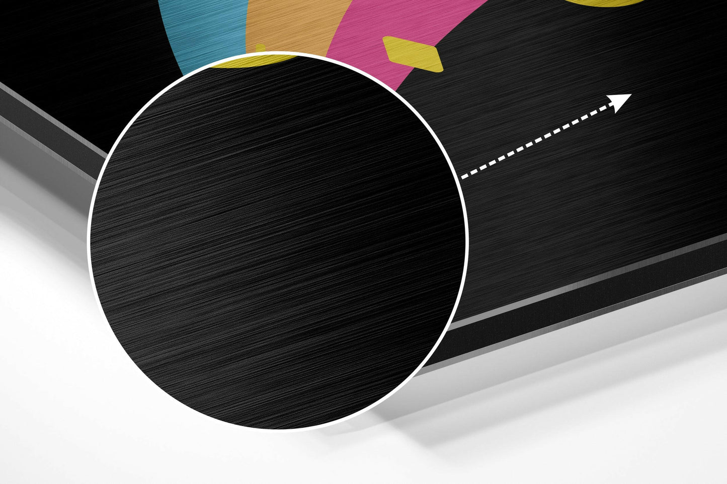 Large black circle with white border on brushed aluminum surface, colorful geometric shapes and directional arrow visible at top.