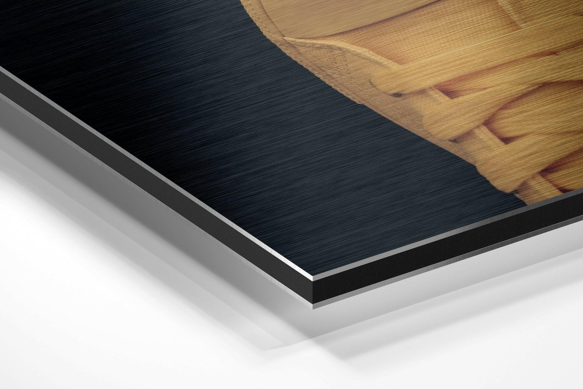 Close-up angled view of layered Dibond wall art showing brushed black aluminum surface with white backing and wooden frame corner visible.