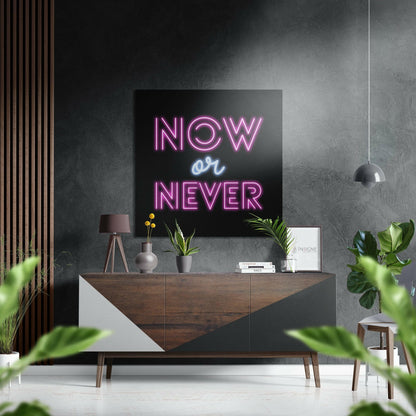 Modern interior styled with neon "NOW or NEVER" sign in pink and blue mounted above wooden dresser with plants and accessories.