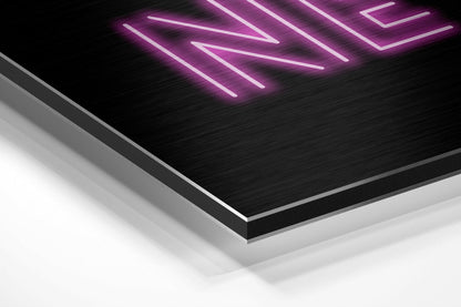 Angled perspective view of brushed aluminum Dibond wall art with magenta neon diagonal lines against black textured surface.