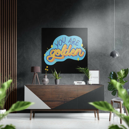 Modern living room interior featuring "You Are Golden" blue and yellow cloud-shaped wall art above wooden console table with plants and pendant lamp.