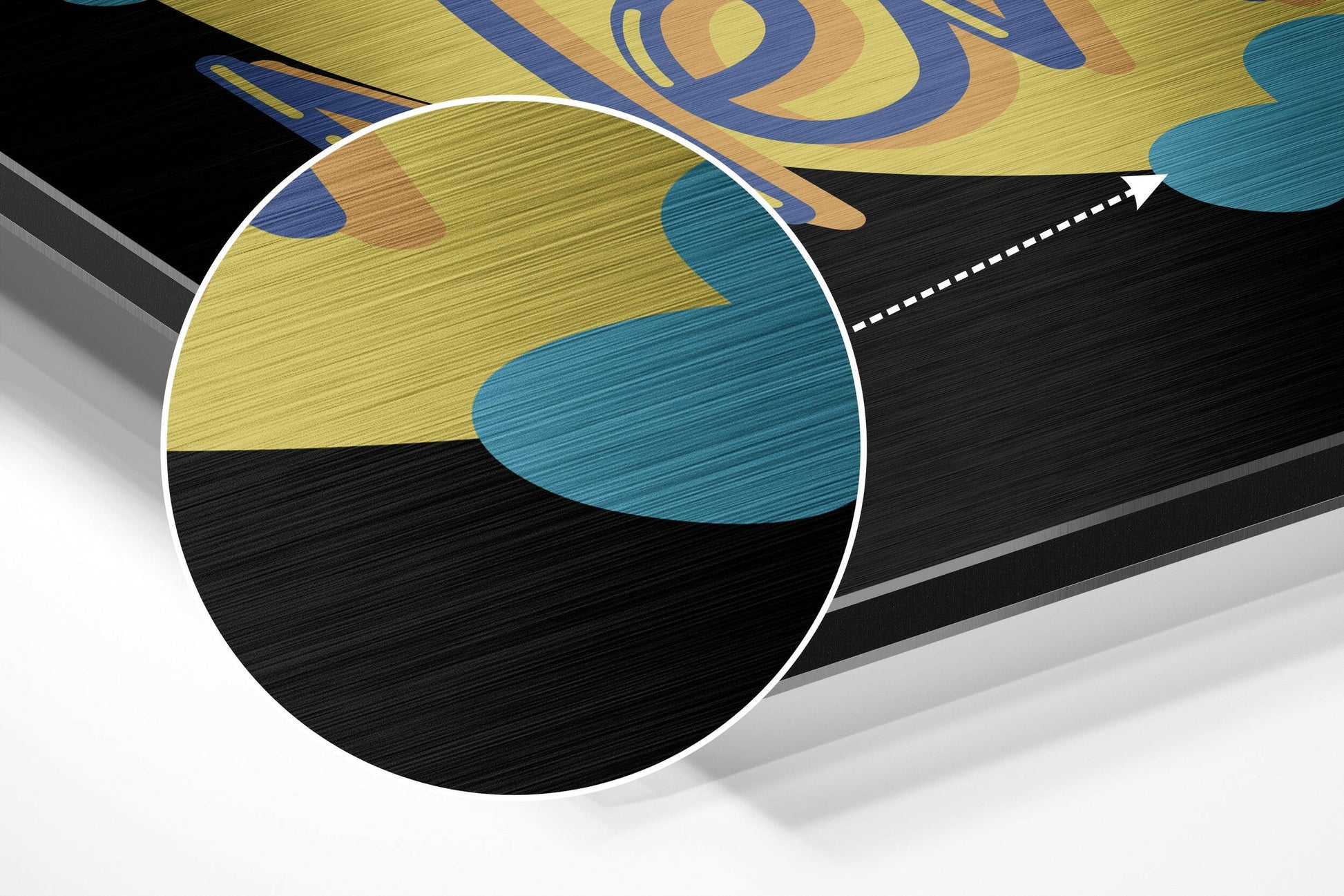 Close-up angled view of brushed aluminum wall art showing yellow, teal, and black abstract design with white circular magnification detail.