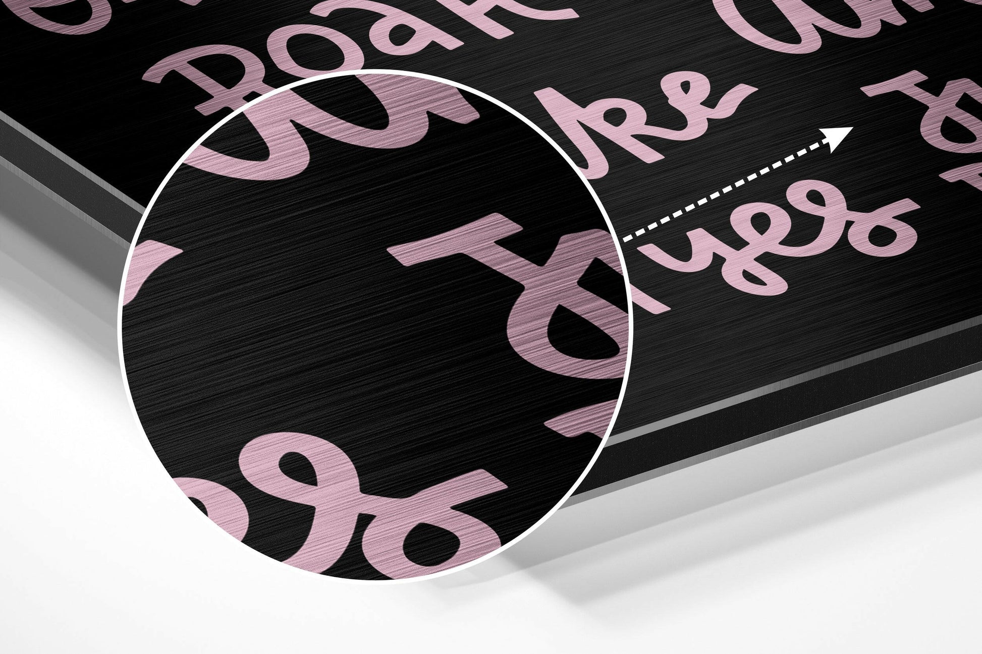 Angled view of brushed aluminum wall art with pink motivational text and numbers on black surface, showing dimensional perspective and metallic finish.