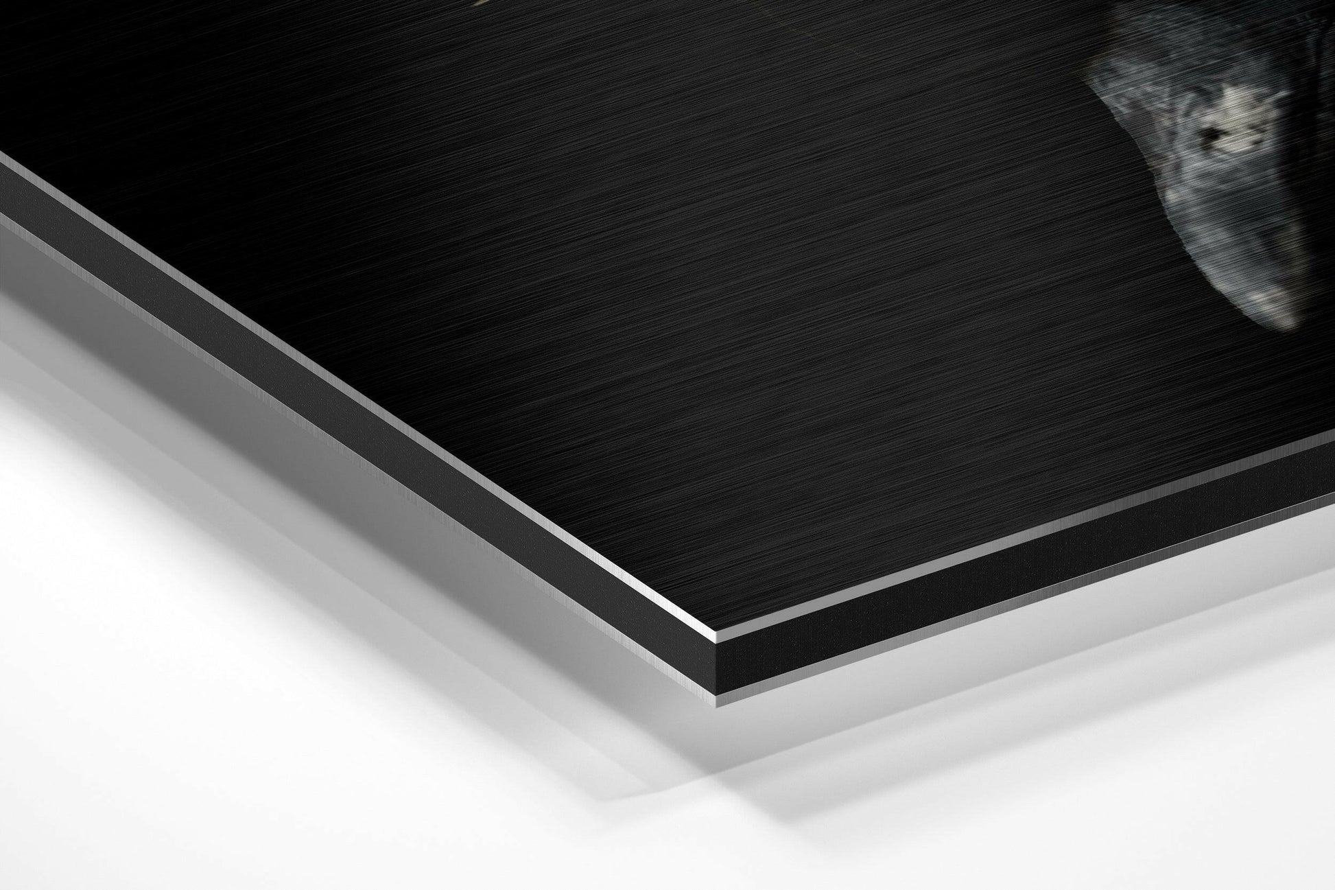 Close-up angled view of layered Dibond panel showing brushed black aluminum surface with white core and silver metal edge trim.