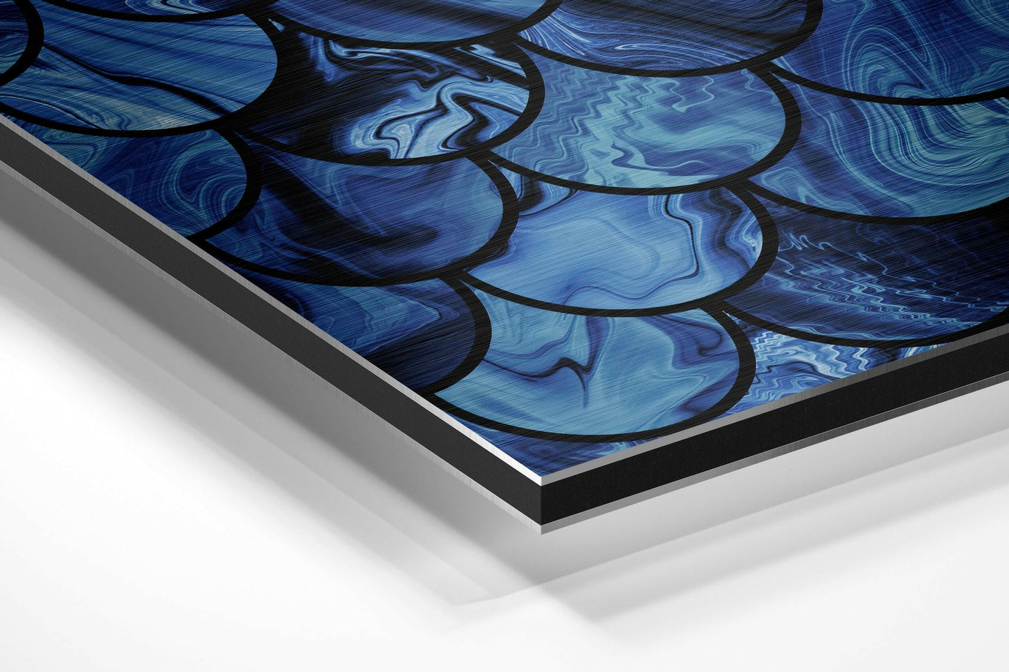 Close-up angled view of blue abstract brushed aluminium Dibond wall art showing layered black-outlined curved shapes with swirling texture patterns.
