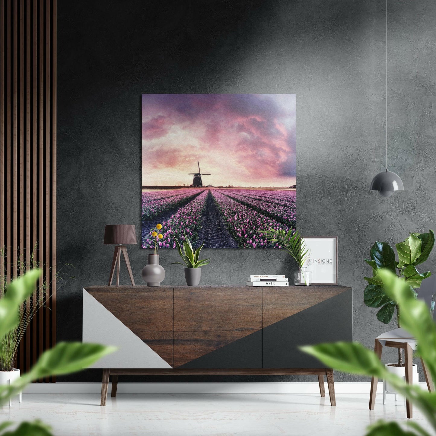 Tulip field with windmill under pink sunset sky displayed on brushed aluminium above wooden dresser in modern room setting.
