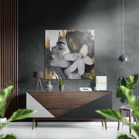 Modern living room interior featuring woman profile artwork with white flower and gold accents displayed above wooden dresser with plants and decor.