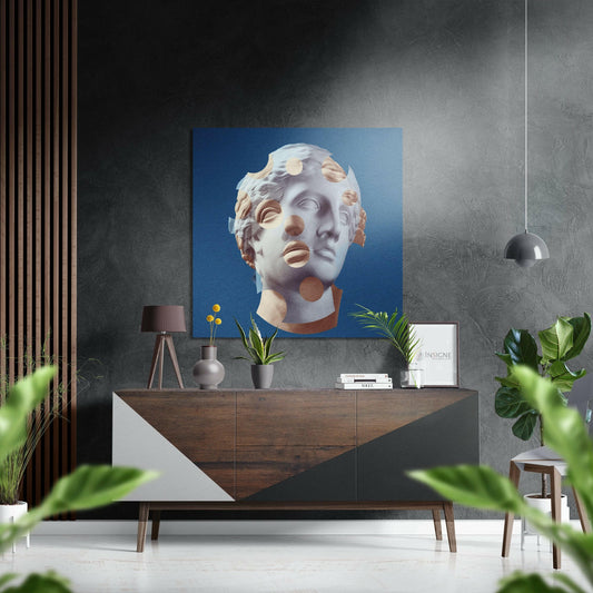 Modern interior with blue artwork of fragmented classical statue head displayed above wooden console table with plants and accessories.