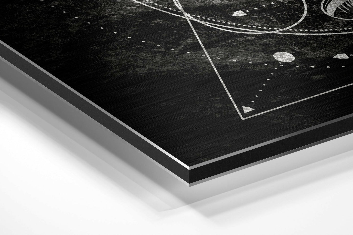 Angled corner view of black brushed aluminum Dibond wall art with white geometric line patterns and dotted details on dark textured surface.