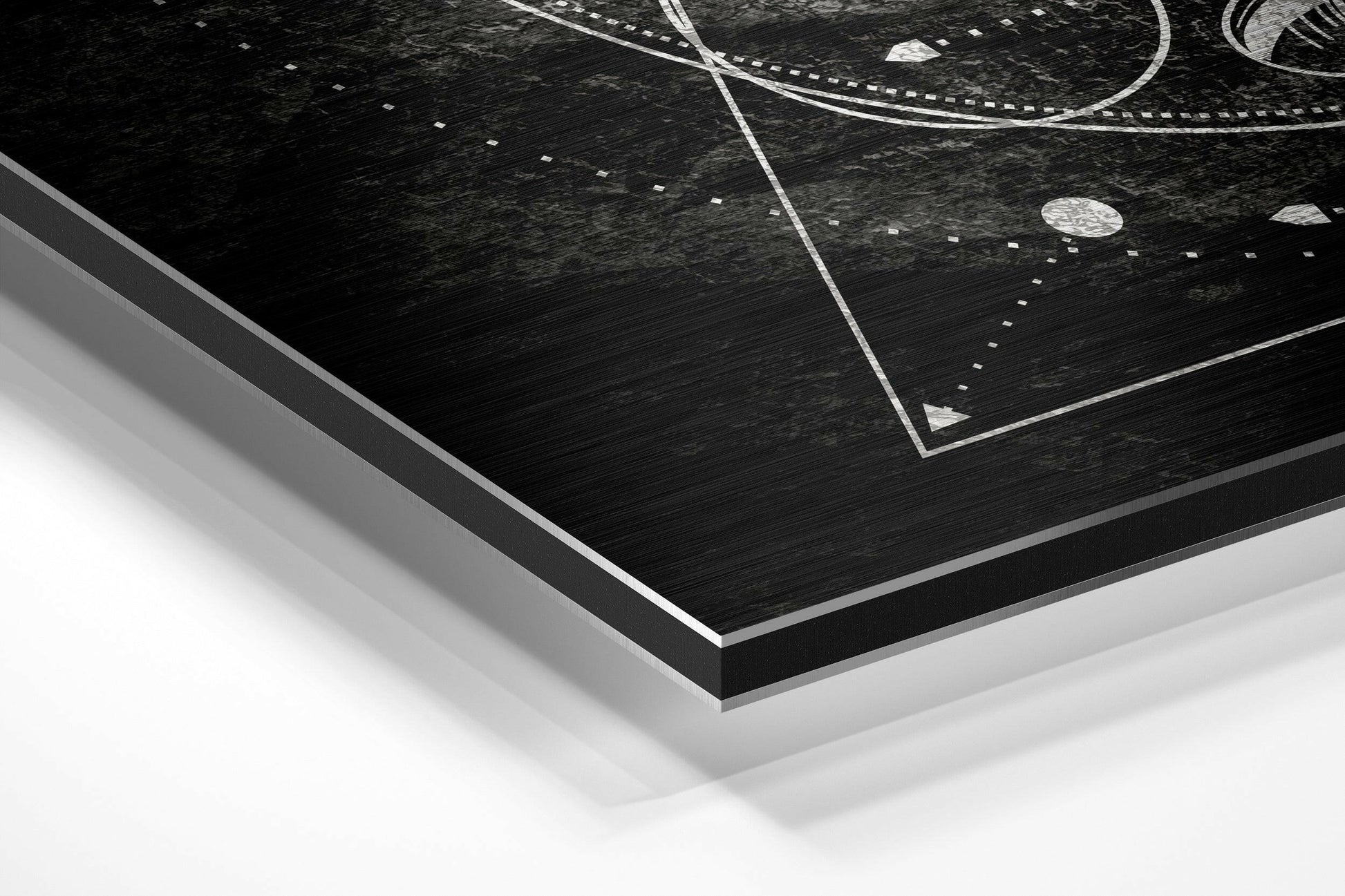 Angled corner view of black brushed aluminum Dibond wall art with white geometric line patterns and dotted details on dark textured surface.