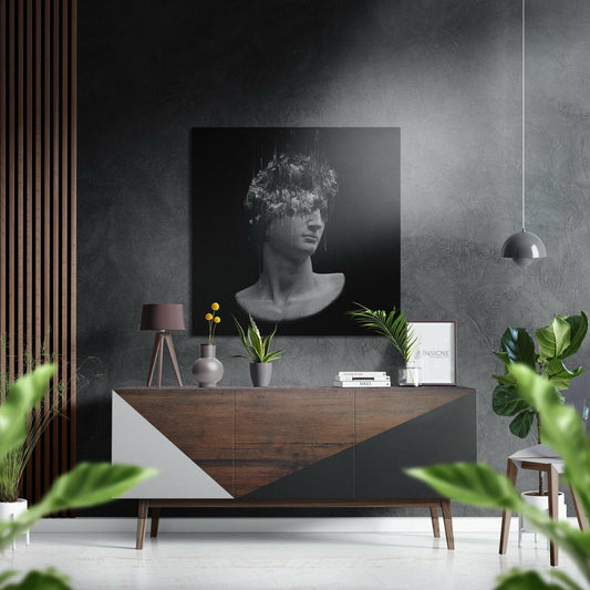 Black and white glitch-effect bust portrait displayed on dark textured wall above wooden dresser in modern interior setting.
