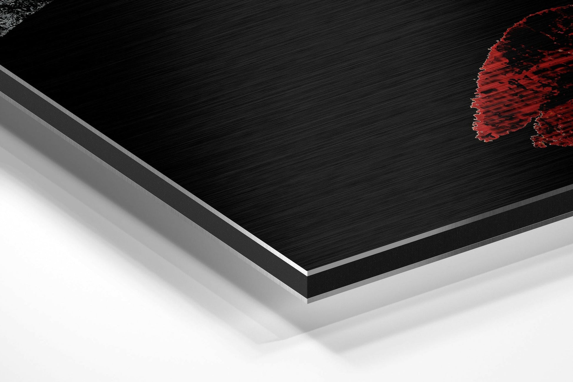 Angled perspective view of layered brushed aluminum Dibond panel with black textured surface, silver edge trim, and red decorative element in upper right corner.