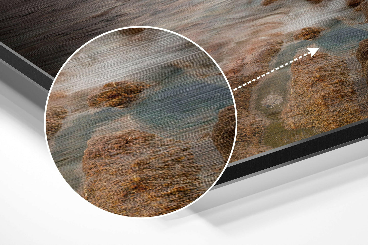 Close-up detail of brushed aluminium Dibond wall art showing coastal rocks and turquoise water with magnified circular inset.