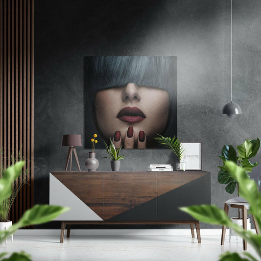 Modern interior vignette featuring gray-haired portrait wall art above wooden dresser with styling accessories and plants.
