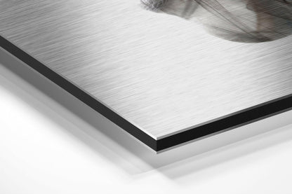 Close-up angled view of brushed aluminum Dibond panel showing layered edge with black border and white backing material.
