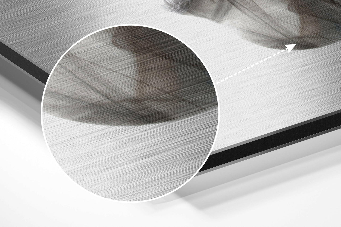Close-up angled view of brushed aluminium Dibond sheet showing textured surface with circular cutout detail and directional arrow marking.
