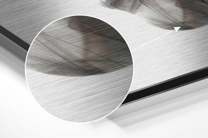 Close-up angled view of brushed aluminium Dibond sheet showing textured surface with circular cutout detail and directional arrow marking.