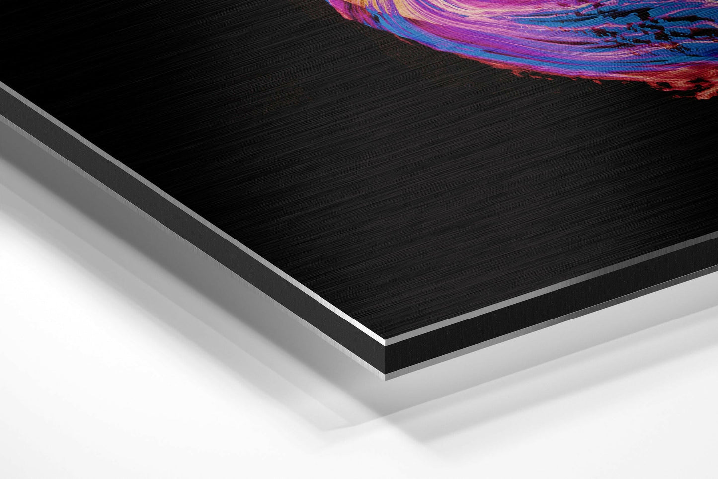 Angled product shot showing layered edge profile of brushed black aluminium Dibond panel with vibrant pink and purple swirled artwork visible at top.