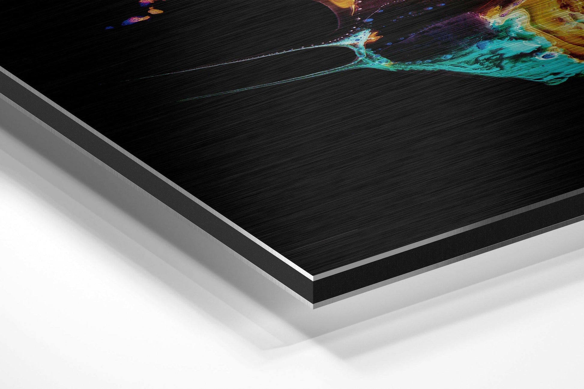 Close-up angled view of layered Dibond panel showing brushed aluminum finish with turquoise and yellow abstract artwork detail visible at top edge.