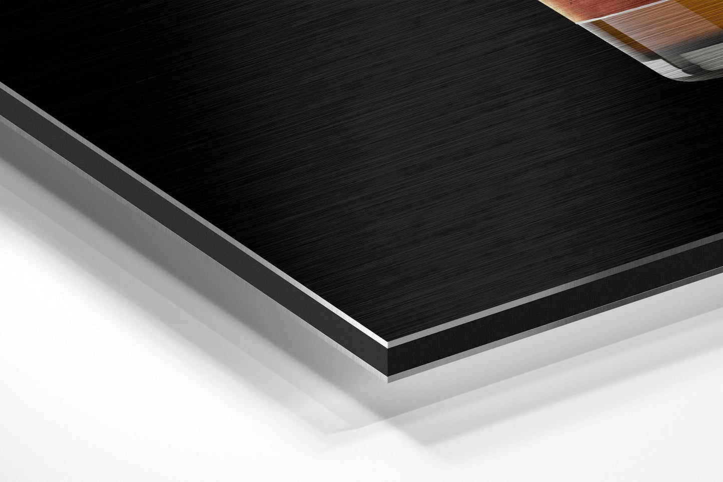 Close-up angled view of layered Dibond panel showing black brushed aluminum surface with silver edge border and white backing layer.