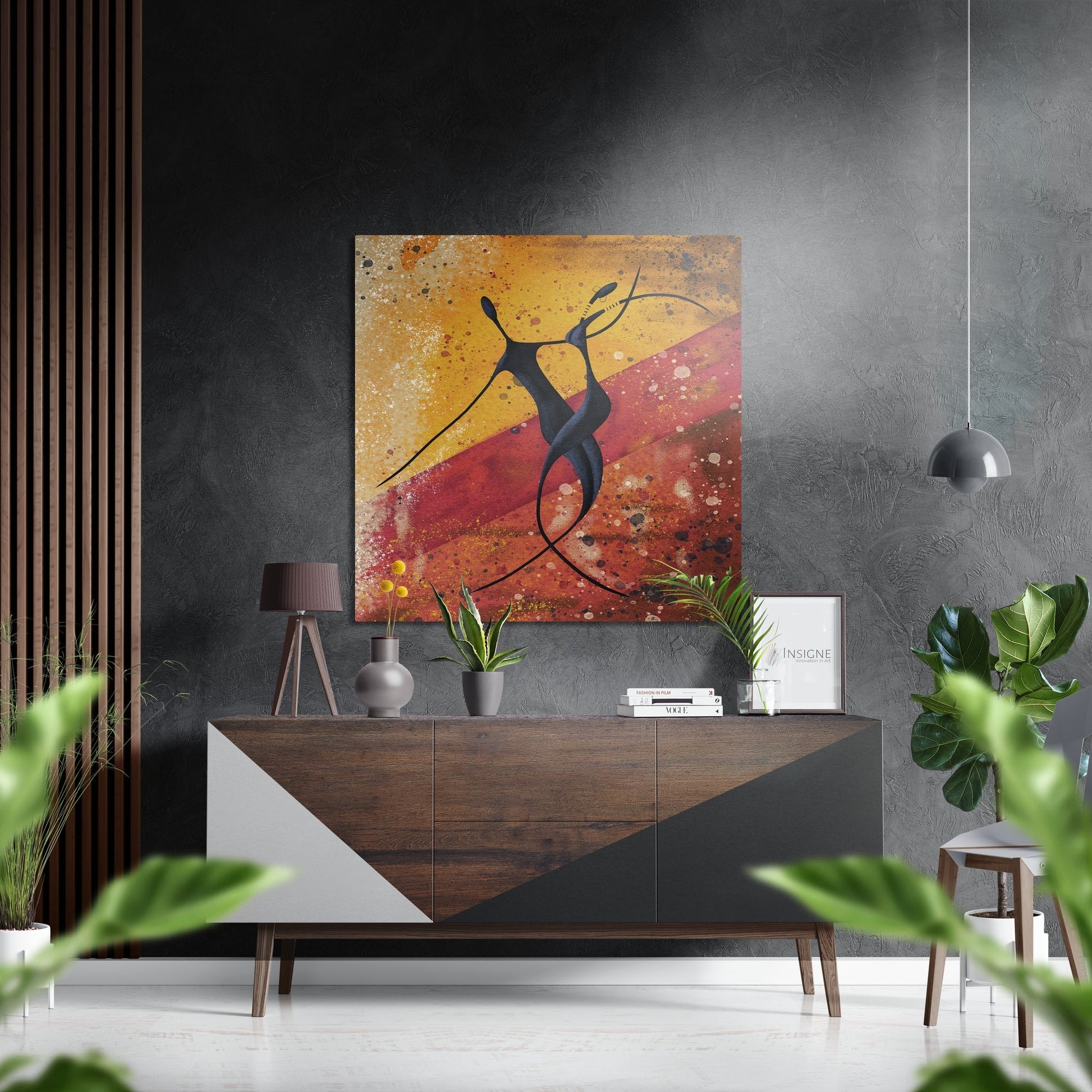 Modern interior with abstract figure artwork featuring warm orange and red tones displayed above wooden sideboard with plants and accessories.
