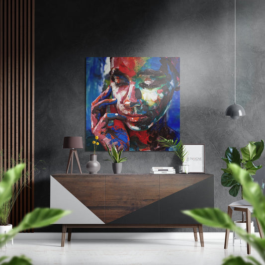 Colorful abstract portrait with red, blue, and yellow brushstrokes displayed above a mid-century wooden console in a modern gray interior.