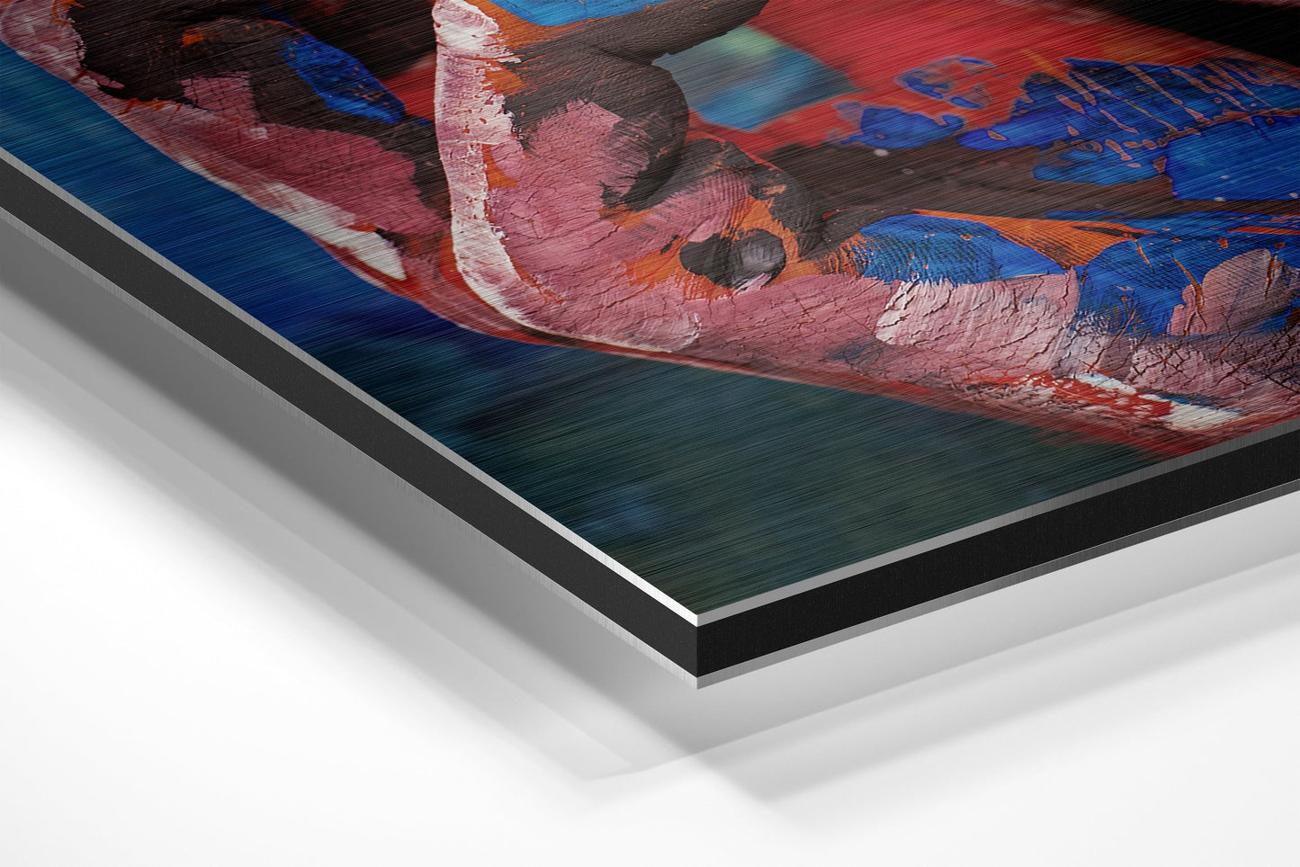 Close-up angled view of brushed aluminium Dibond wall art showing layered edge detail with red, blue, pink, and orange abstract painted surface.