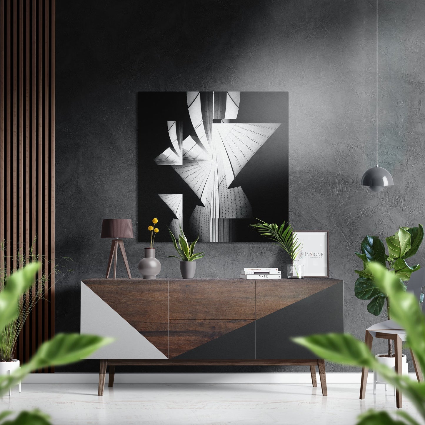 Modern monochrome architectural photograph mounted above wooden sideboard in minimalist interior setting with plants and pendant light.