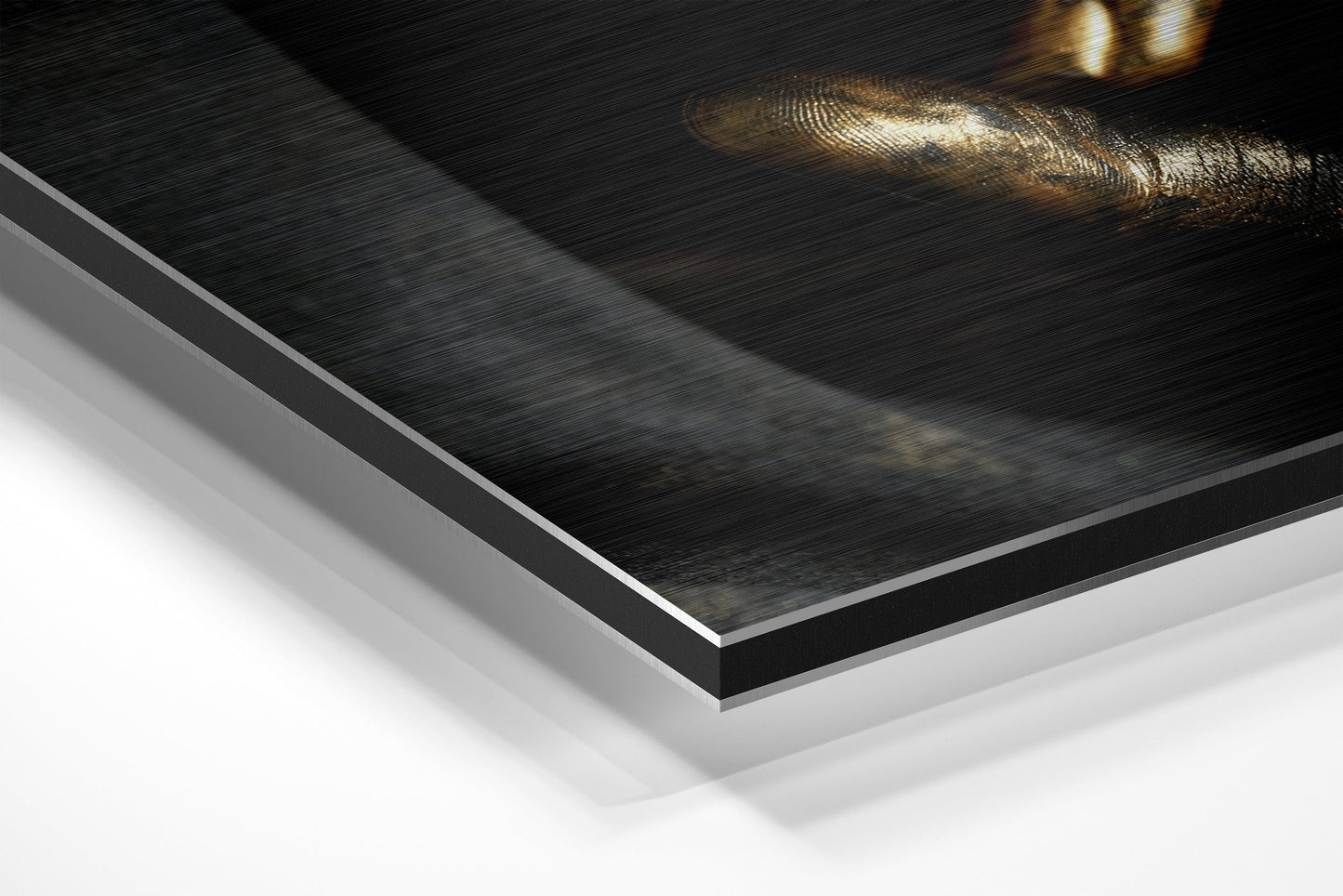 Close-up angled view of layered Dibond wall art showing brushed black aluminum surface with white backing board and gold-toned decorative element.
