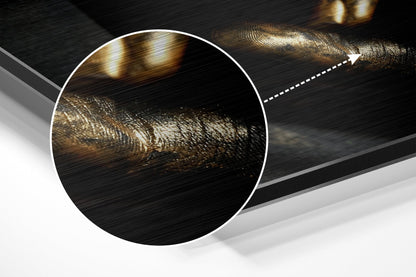 Close-up detail of brushed aluminum surface showing gold and bronze metallic brushstrokes with directional arrow indicator.