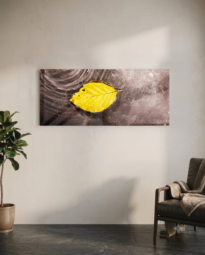 Yellow leaf glass wall art displayed on white wall above chair, showing bright yellow autumn leaf on dark textured background.