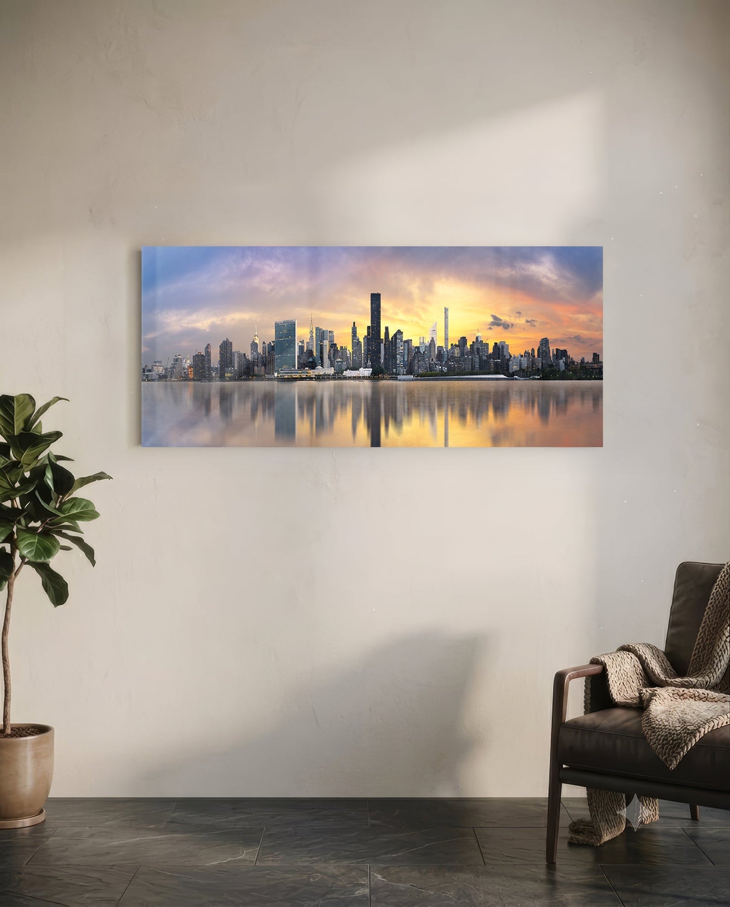 Horizontal glass wall panel displaying Manhattan skyline at sunset with golden sky and water reflections, mounted on white wall above leather chair.