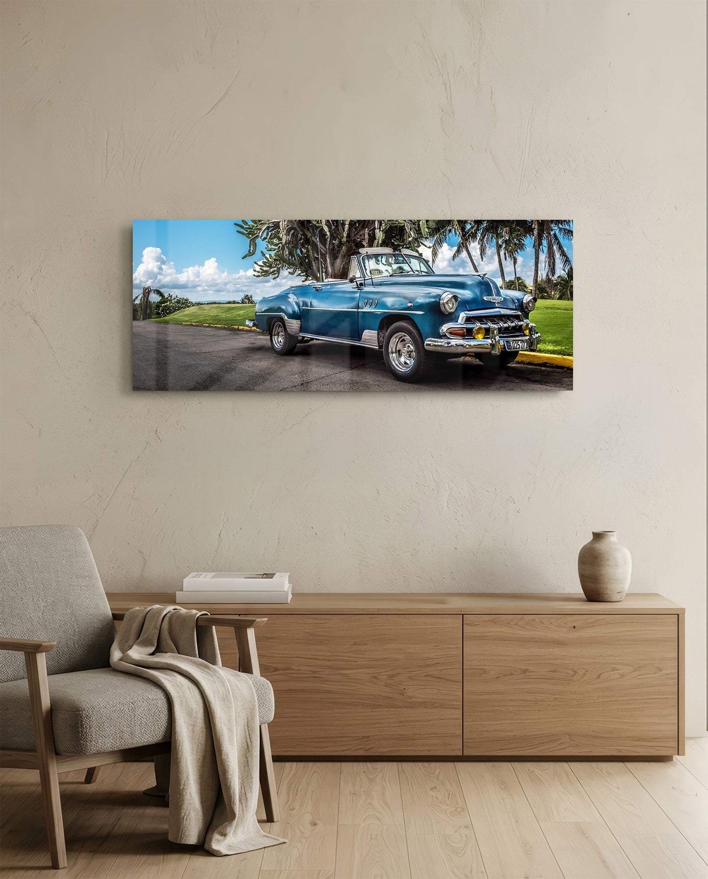 Classic blue convertible car displayed on glass wall art above wooden dresser in modern living room setting.
