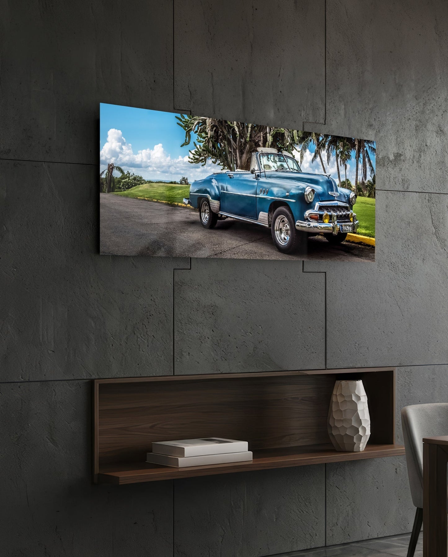 Blue vintage convertible car displayed on glass wall art mounted above wooden shelf against concrete wall.