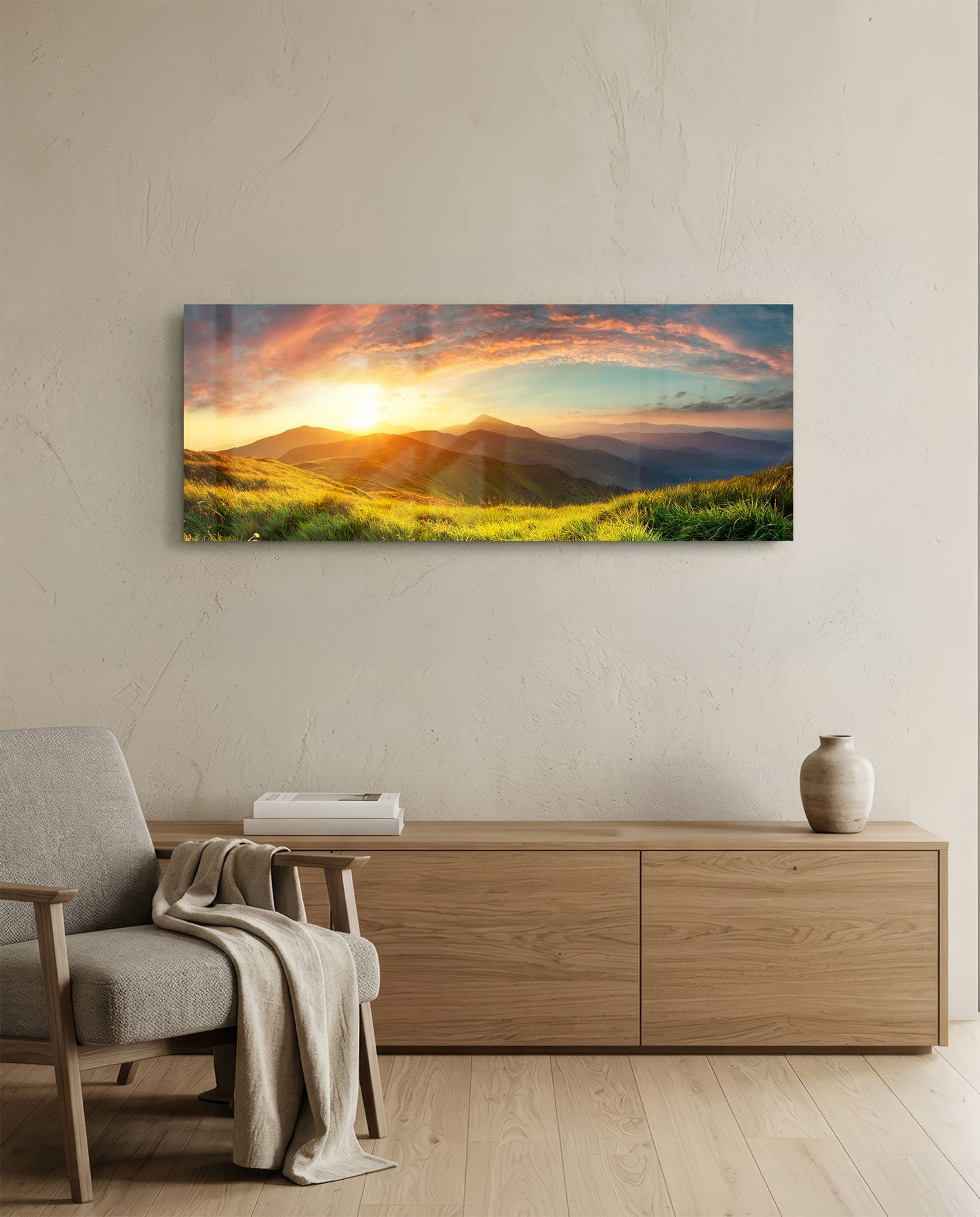 Panoramic glass wall art mounted above wooden dresser showing golden sunset over rolling green hills and distant mountains.
