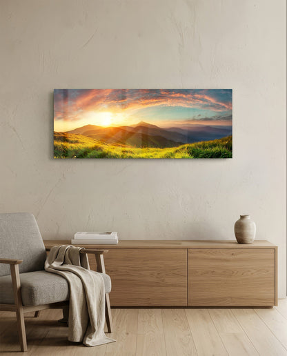 Panoramic glass wall art mounted above wooden dresser showing golden sunset over rolling green hills and distant mountains.