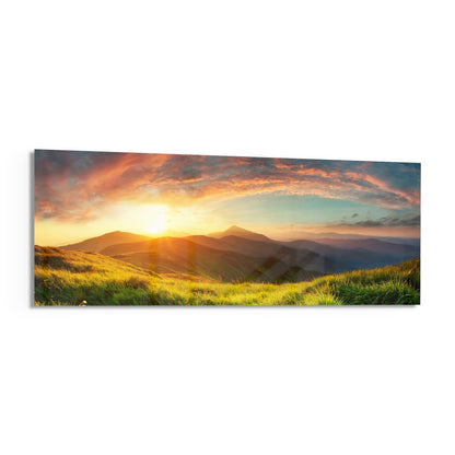 Golden sunrise over rolling green hills and distant mountains with dramatic orange and yellow clouds.