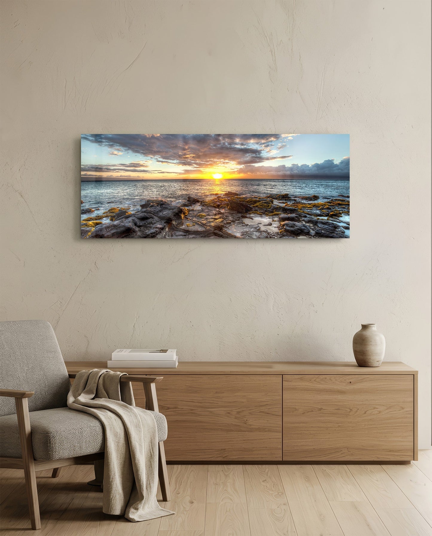 Sunset glass wall art displayed horizontally above wooden dresser in minimalist room with beige chair.